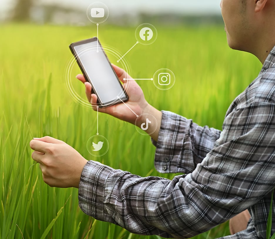 Farmer looking a mobile device surrounded by social media logos
